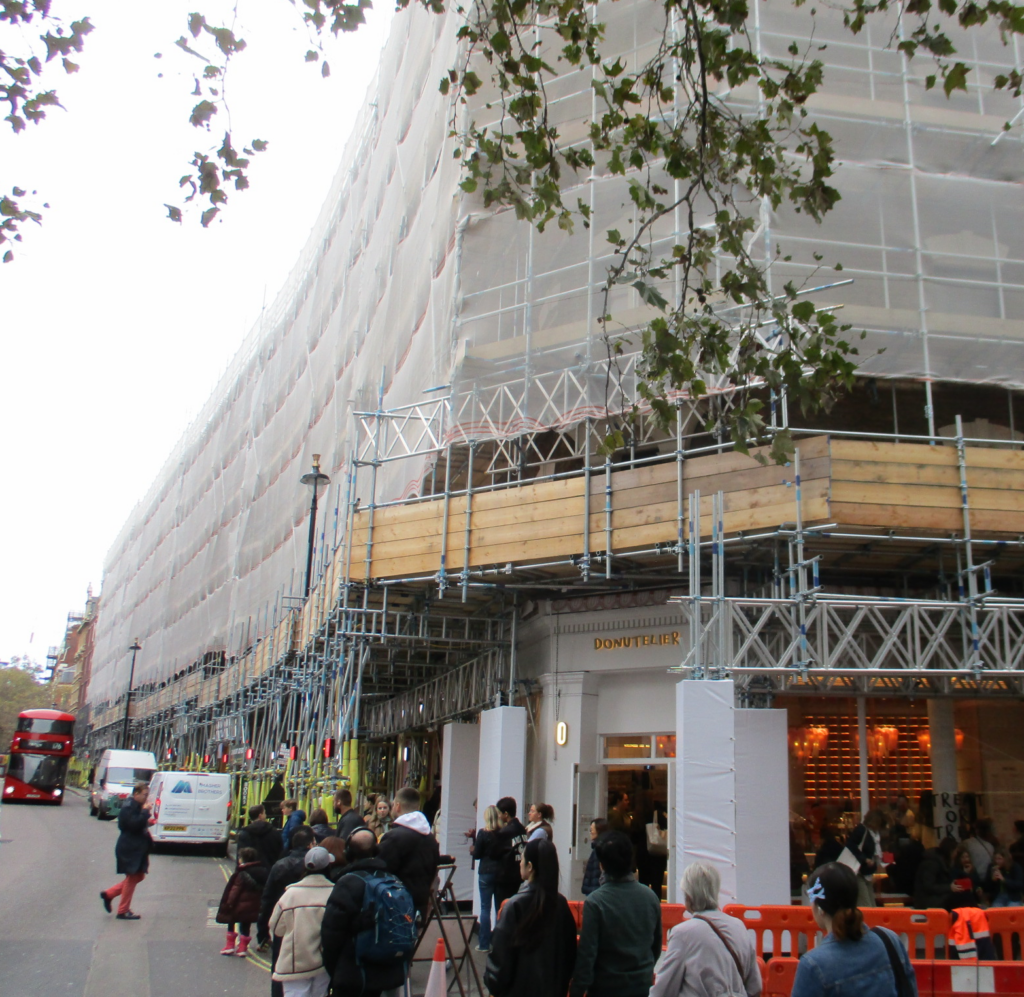 Image of Sandringham Flats with scaffolding and white bird netting, with Donutelier in foreground