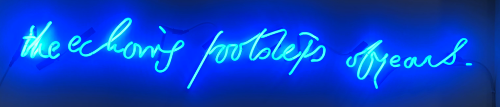 Blue neon sign reading ‘The echoing footsteps of years’